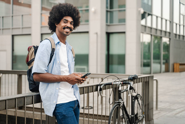 Portrait of African American Man with bicycle and cell phone in the city - Photo, Image
