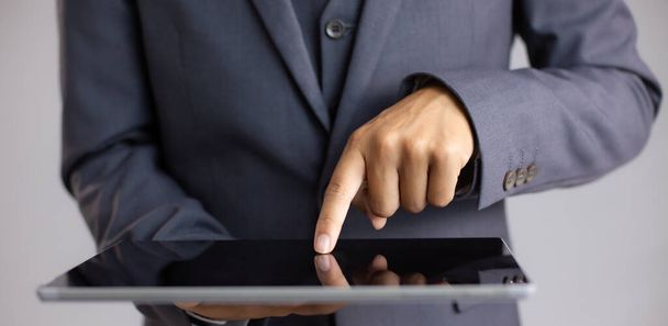Close up businessman finger touching and pointing on black blank screen tablet grey background.	 - 写真・画像