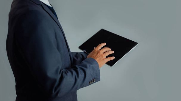 アジアのビジネスマンのスーツタブレットに触れる黒画面グレーの背景 - 写真・画像
