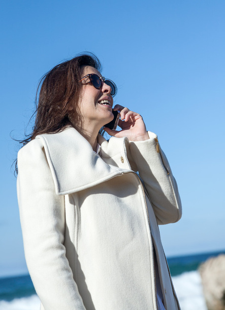 Attractive woman talking by phone to the sea - Fotó, kép