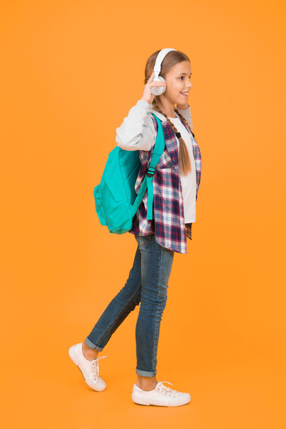 i am ready. hipster girl care backpack. schoolgirl casual style hold school bag. autumn kid fashion. child listen music headset. childhood education and development. happy childrens day. audio book. - Foto, afbeelding