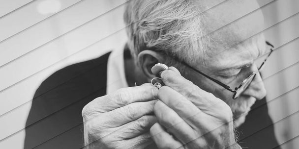 Senior man putting hearing aids, geometric pattern - Foto, afbeelding