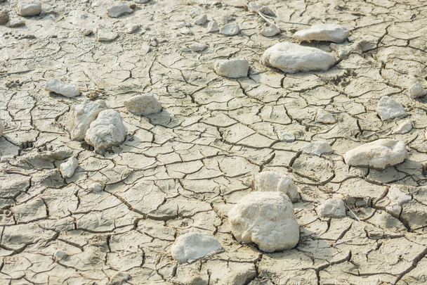 weiße Steine auf dem Boden aus einem ausgetrockneten Teich mit Rissen Klimawandel - Foto, Bild