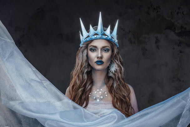 Shot of ice maiden with make up dressed in crown and cloak. - Фото, изображение
