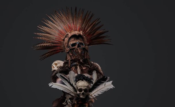Shot of scary aztec necromancer holding staff with skull against grey background. - Foto, immagini