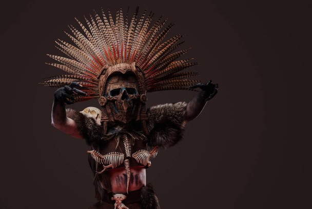 Strzał przerażającej kobiety zombie ubranej w ciemne, aborygeńskie stroje i ceremonialne nakrycie głowy. - Zdjęcie, obraz