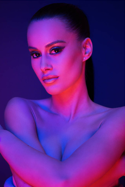 Sensual young brunette model posing in lingerie lit by very colorful lights. - Fotoğraf, Görsel