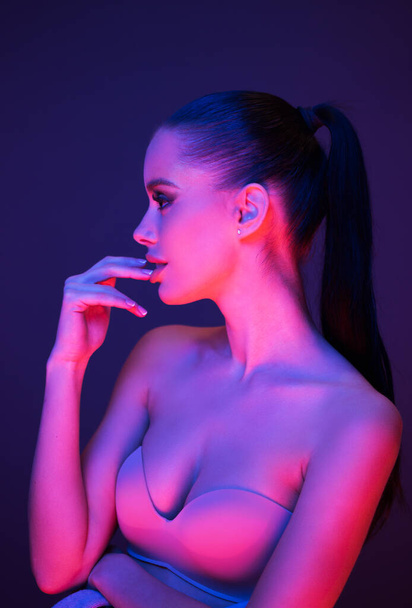 Sensual young brunette model posing in lingerie lit by very colorful lights. - Foto, imagen