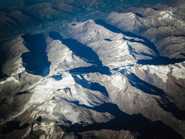 'λπεις, θέα των βουνών από το παράθυρο του αεροπλάνου. Η έννοια της κάμψης γης και της φύσης. - Φωτογραφία, εικόνα