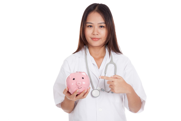 Młodych azjatyckich kobiet lekarza punkt do świni banku monety - Zdjęcie, obraz