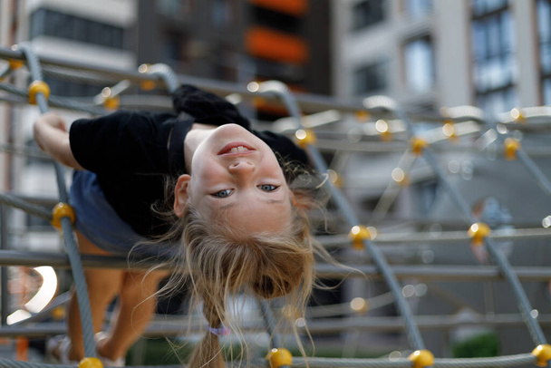 Portrait of a child upside down with positive emotions on the playground. Happy girl. - Фото, зображення