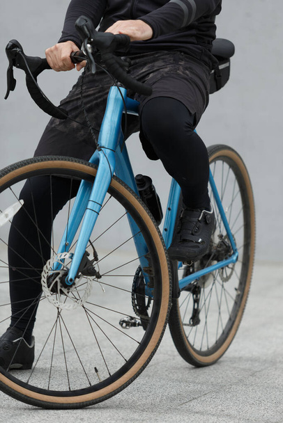 Close-up, gravel bike with a cyclist in black clothes. Outfit for travel and sports. - Photo, Image