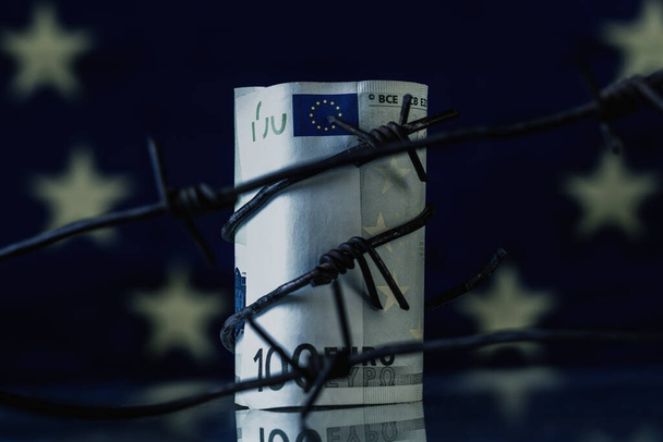 Gazdasági hadviselés, szankciók és embargórombolás. Szögesdróttal ellátott uniós pénzeszközök az Európai Unió zászlaja ellen. - Fotó, kép