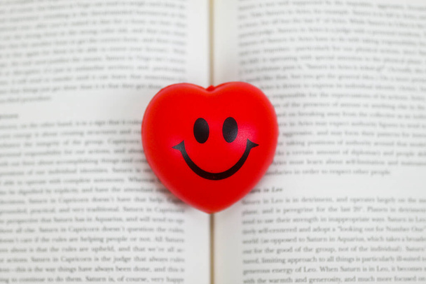 corazón rojo sonriente en medio del libro de texto fondo borroso enfoque selectivo, lectura de conciencia plena, pacífico, hábito, concentrado, felicidad concepto de lectura estilo de vida me encanta lo que lees - Foto, imagen