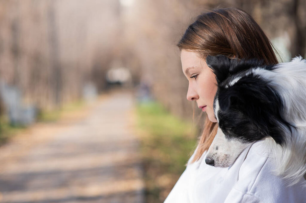 Kaukasische Frau umarmt Border Collie im Herbst Park. Porträt eines Mädchens mit Hund - Foto, Bild
