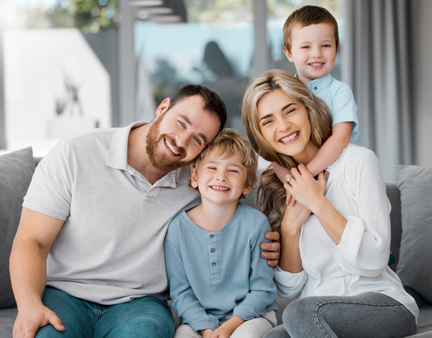 Portrait of smiling caucasian family relaxing together on a sofa at home. Loving parents bonding with carefree playful little sons. Happy kids spending quality time with mom and dad. - Valokuva, kuva