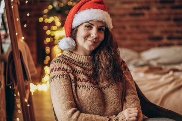 Egy fiatal nő ül egy székben karácsony estéjén. Boldog karácsonyt!. - Fotó, kép