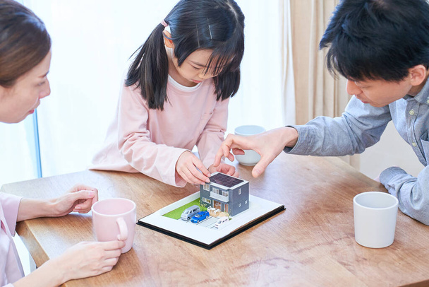 Uma família discutindo enquanto olha para um modelo de uma casa separada - Foto, Imagem