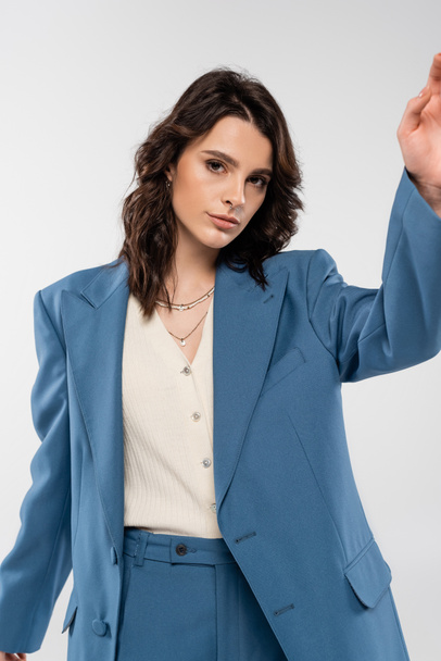young fashionable woman in blue suit looking at camera while posing isolated on grey - Фото, зображення