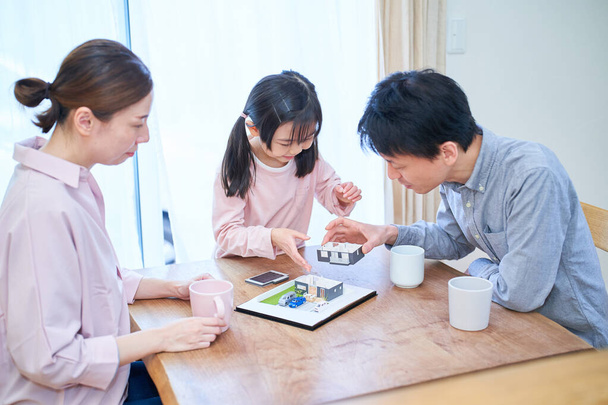 Μια οικογενειακή συζήτηση κοιτάζοντας ένα μοντέλο μιας μονοκατοικίας - Φωτογραφία, εικόνα