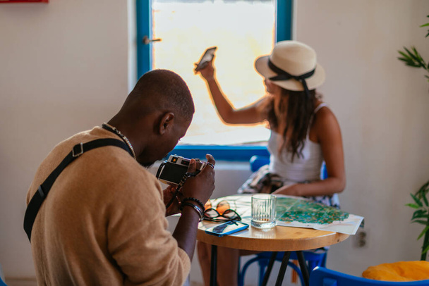 Μια όμορφη γυναίκα βγάζει σέλφι ενώ ο φίλος της βγάζει φωτογραφία με την κάμερα του. - Φωτογραφία, εικόνα