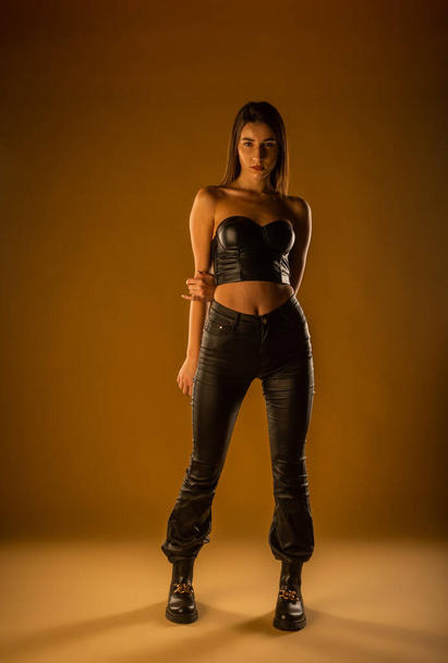 Sexy Mädchen in schwarzer Lederkleidung: Top, Hose und Stiefel - Foto, Bild