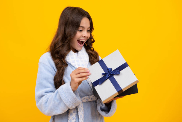 Amazed teen girl. Child with gift present box on isolated background. Presents for birthday, Valentines day, New Year or Christmas. Excited expression, cheerful and glad - Photo, Image