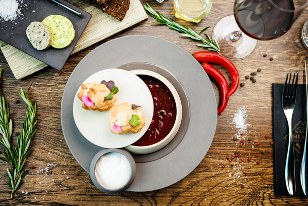 Cékla leves Borscht hússal és tejszínnel egy tálban. Ízletes egészséges ukrán hagyományos ételeket closeup szolgált fel ebédre az asztalon a modern ínyenc konyha étterem. - Fotó, kép