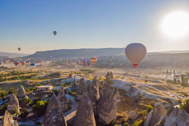 Colorful hot air balloons flying over at fairy chimneys valley in Nevsehir, Goreme, Cappadocia Turkey. Spectacular panoramic drone view of the underground city and ballooning tourism. High quality. - 写真・画像