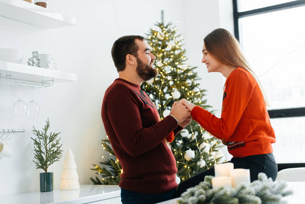 An attractive couple are opening their Christmas gifts near Christmas tree. - Fotoğraf, Görsel