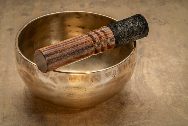 handmade tibetan singing bowl with a mallet on a textured bark paper, sound therapy for healing, relaxation and meditation - Foto, immagini