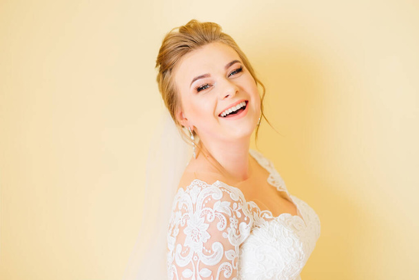 щаслива наречена посміхається і дивиться на камеру. біла весільна сукня з візерунком
. - Фото, зображення