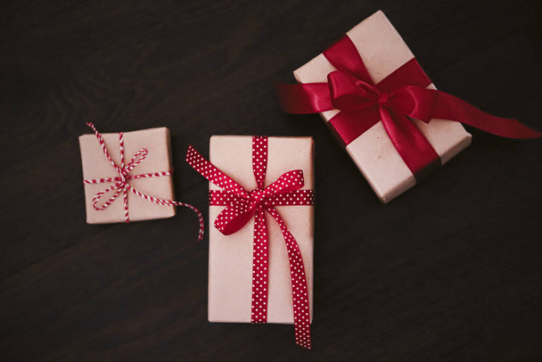 Geschenke und traditionelle Weihnachtsgeschenke, klassische Geschenkschachteln auf hölzernem Hintergrund, Geschenk in Bastelpapier mit roter Schleife verpackt, rustikaler Landhausstil für saisonale Feiertage. - Foto, Bild