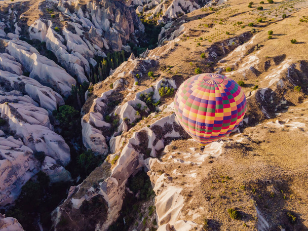 Colorful hot air balloons flying over at fairy chimneys valley in Nevsehir, Goreme, Cappadocia Turkey. Spectacular panoramic drone view of the underground city and ballooning tourism. High quality. - Fotoğraf, Görsel