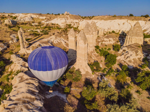 Colorful hot air balloons flying over at fairy chimneys valley in Nevsehir, Goreme, Cappadocia Turkey. Spectacular panoramic drone view of the underground city and ballooning tourism. High quality. - Fotó, kép