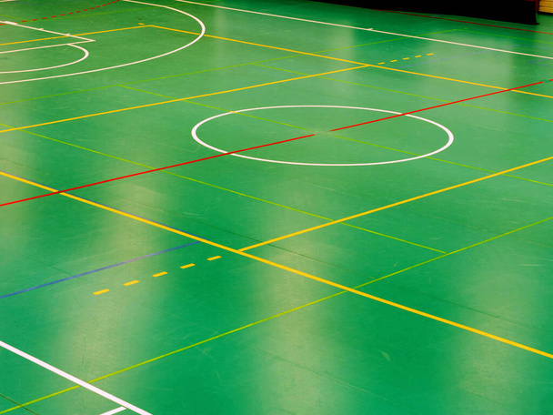 Lichtreflexion im grünen Indoor-Spielfeld für Basketball oder Handball. Interieur der Schulsporthalle - Foto, Bild