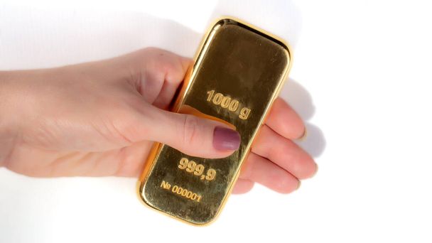 Een kilo goud in de hand van een vrouw, geïsoleerd op een witte achtergrond.. - Foto, afbeelding