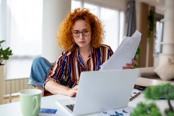 Увлеченная бизнес-женщина, использующая ноутбук дома, смотрящая на экран, читающая или пишущая электронную почту, сидящая на диване, студентка, выполняющая домашнюю работу, работающая над исследовательским проектом в Интернете - Фото, изображение