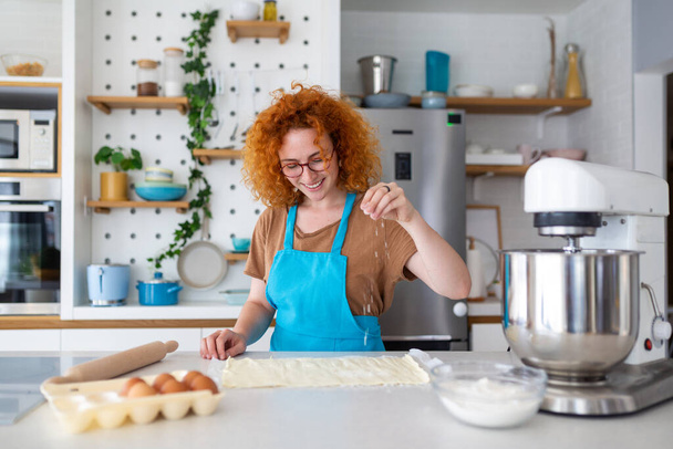 Koncepcja pieczenia. Portret radosnej kobiety Kneading Ciasto we wnętrzu kuchni, Wesoła kobieta w fartuchu zabawy podczas przygotowywania domowego ciasta, - Zdjęcie, obraz