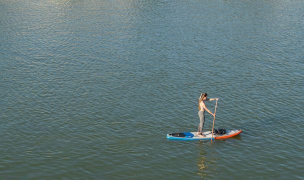 Girl standing on a paddle surf board. Girl paddle surfing in the river.  - Valokuva, kuva