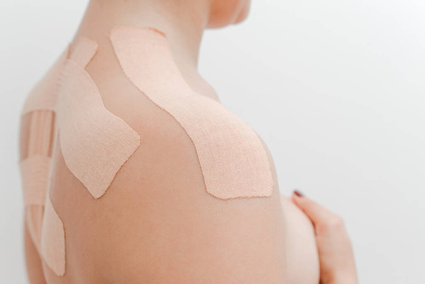 Women's body with kinesio tape on the back and shoulders. Kinesiology taping concept. White background. Close-up view - Fotografie, Obrázek