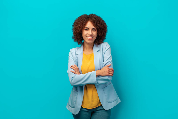 Portrait of a smiling successful African American woman with curly hair in a jacket on a blue background, Hiring, career concept - Fotó, kép