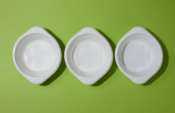 Білий порожній пластиковий суп на зеленому фоні, вид зверху
 - Фото, зображення