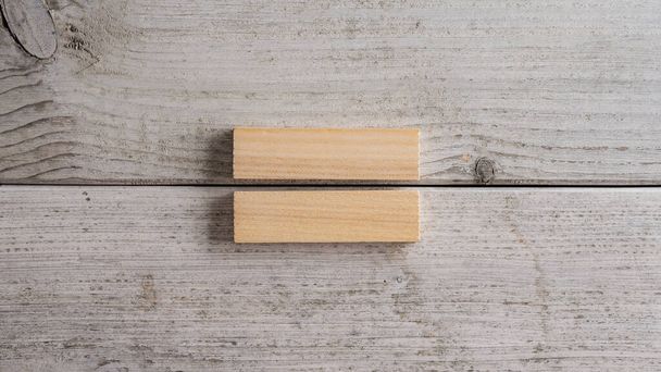 Two simple blank wooden pegs placed over textured white background. - Foto, afbeelding