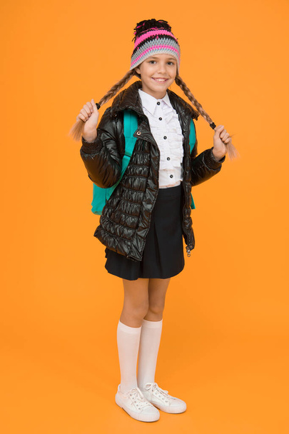 Fashion concept. Warm clothing. Buy clothes for school season. Schoolgirl fashion outfit. Fall autumn winter. Child with backpack. Fashion shop. Girl wear knitted hat and jacket yellow background. - Photo, Image