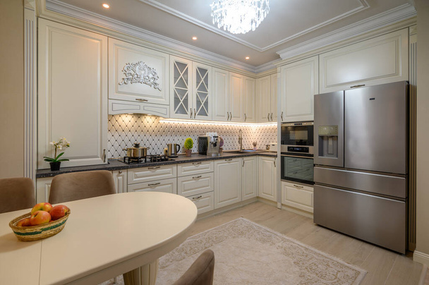 Mooie beige keuken met een grote eettafel en state-of-the-art apparatuur - Foto, afbeelding
