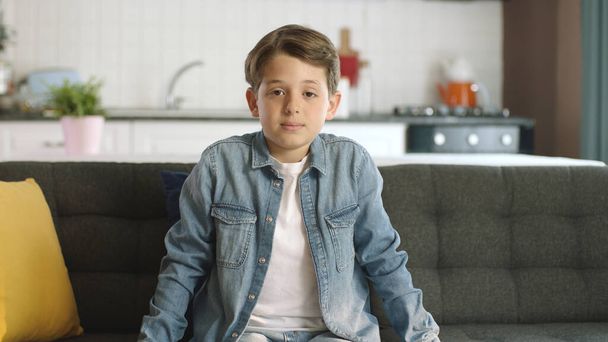 Egy unatkozó szomorú fiú portréja otthon. Egy magányos és unatkozó fiú portréja, aki otthon ül a kanapén, depressziósan és szomorúan. Emberek és negatív érzelmek fogalma. - Fotó, kép