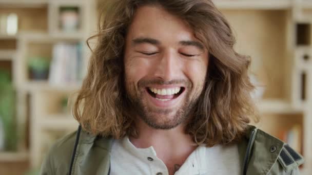 Счастливый человек, лицо и улыбка, смеясь над смешной комической шуткой, в то время как застенчивый, кареглазый и довольствующийся в помещении идеальными зубами. Портрет красивого австралийского мужчины с длинными волосами, бородой и позитивным настроем. - Кадры, видео