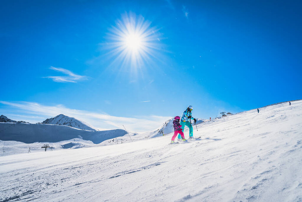 Matka i córka przygotowują się do zjazdu na stok narciarski. Słoneczny dzień na nartach zimowych w Andorze, El Tarter, Pireneje - Zdjęcie, obraz