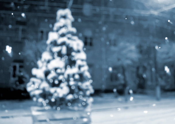 Різдвяна ялинка вкривала сніг, світячи різнокольорові вогні під час снігопадів на відкритому повітрі. Абстрактний різдвяний новорічний фон. Розмитий сніговий зимовий фон. Світлове мерехтіння. Синій колір
 - Фото, зображення